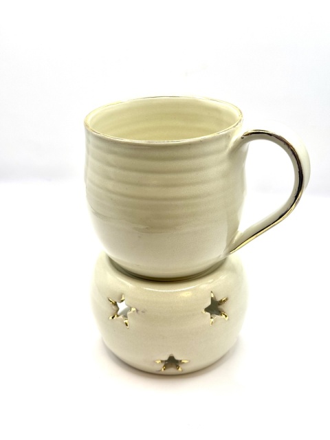 Kremowy, złocony kubek ceramiczny z podgrzewaczem.