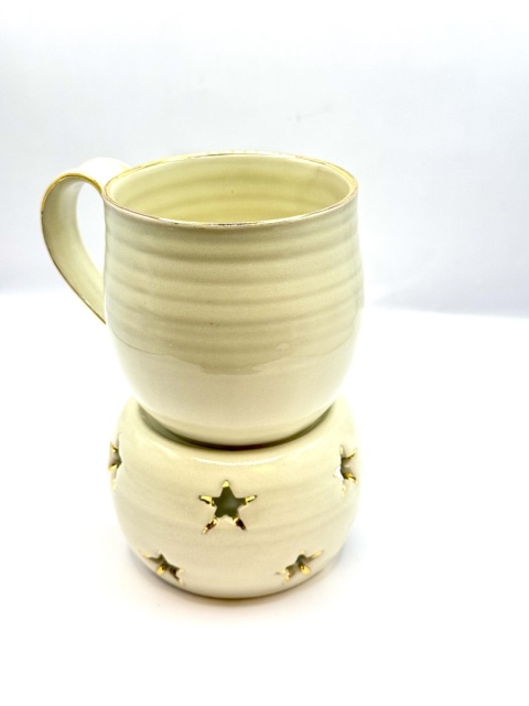 Kremowy, złocony kubek ceramiczny z podgrzewaczem.