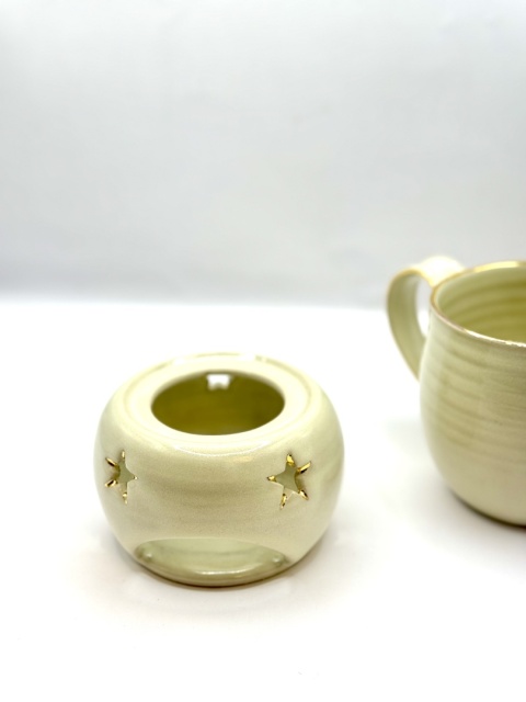 Kremowy, złocony kubek ceramiczny z podgrzewaczem.